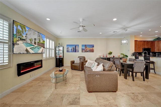 living area featuring recessed lighting, baseboards, crown molding, and a glass covered fireplace