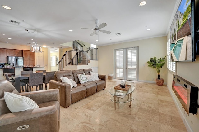 living room featuring light tile patterned flooring, ceiling fan with notable chandelier, and ornamental molding