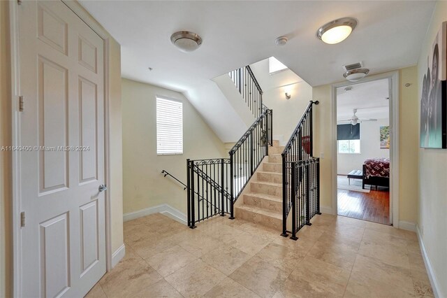 staircase with ceiling fan, a skylight, and hardwood / wood-style floors