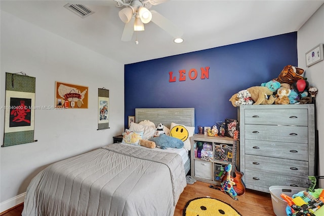 bedroom featuring a ceiling fan, baseboards, visible vents, and wood finished floors