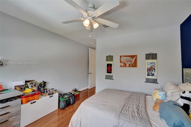 bedroom featuring a ceiling fan, visible vents, and wood finished floors