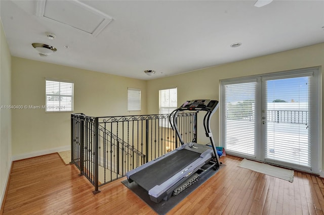 workout room featuring attic access, baseboards, and wood finished floors