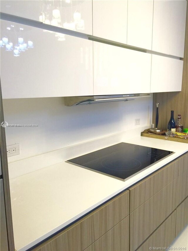 kitchen with black electric cooktop and white cabinetry