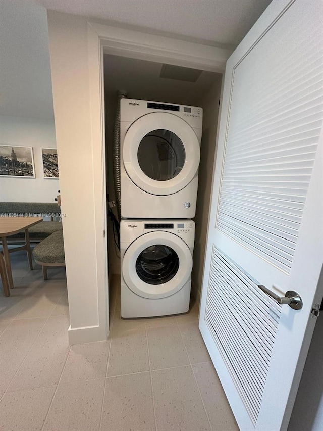 laundry room featuring light tile patterned floors and stacked washing maching and dryer