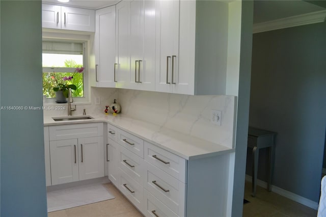 kitchen featuring white cabinetry, light tile patterned floors, backsplash, ornamental molding, and sink