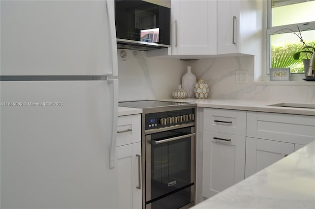 kitchen featuring tasteful backsplash, sink, white cabinets, range with electric cooktop, and white fridge