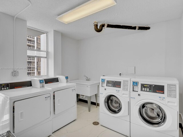 clothes washing area featuring light tile patterned flooring, a textured ceiling, and washer and dryer