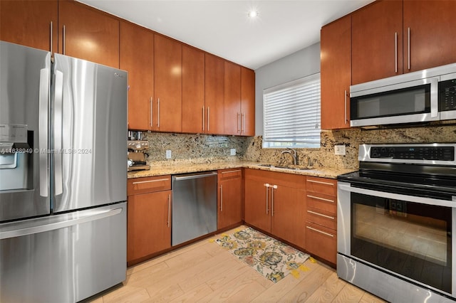 kitchen featuring light stone counters, decorative backsplash, stainless steel appliances, and light hardwood / wood-style floors