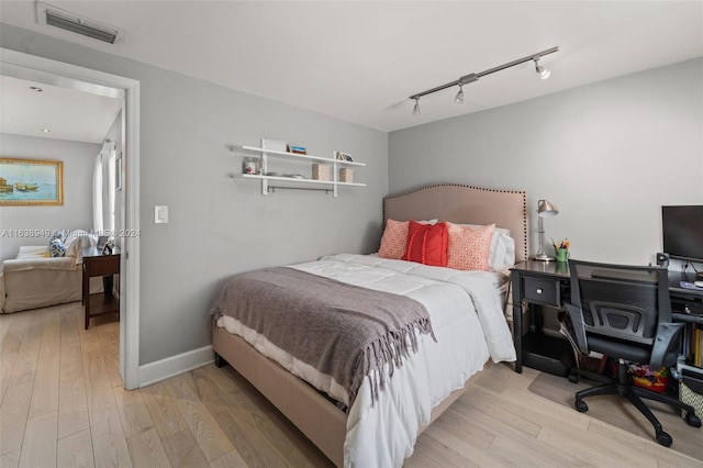 bedroom featuring rail lighting and light hardwood / wood-style flooring