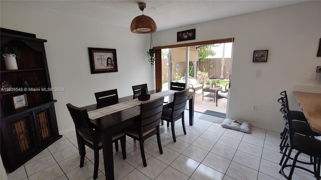 dining space with a textured ceiling and light tile patterned floors