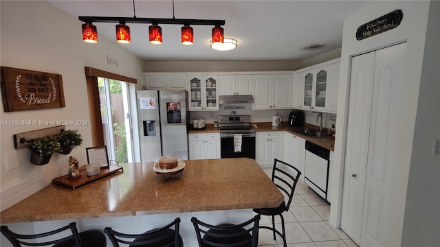 kitchen featuring kitchen peninsula, white cabinets, sink, pendant lighting, and stainless steel appliances