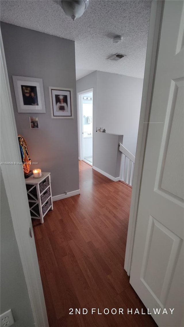 hallway with dark hardwood / wood-style floors and a textured ceiling