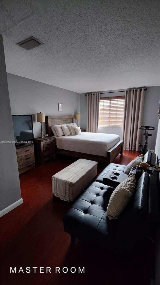 bedroom featuring a textured ceiling and dark hardwood / wood-style floors