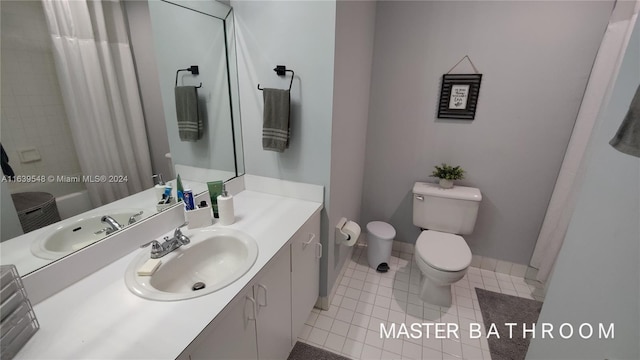 bathroom with toilet, vanity, and tile patterned flooring