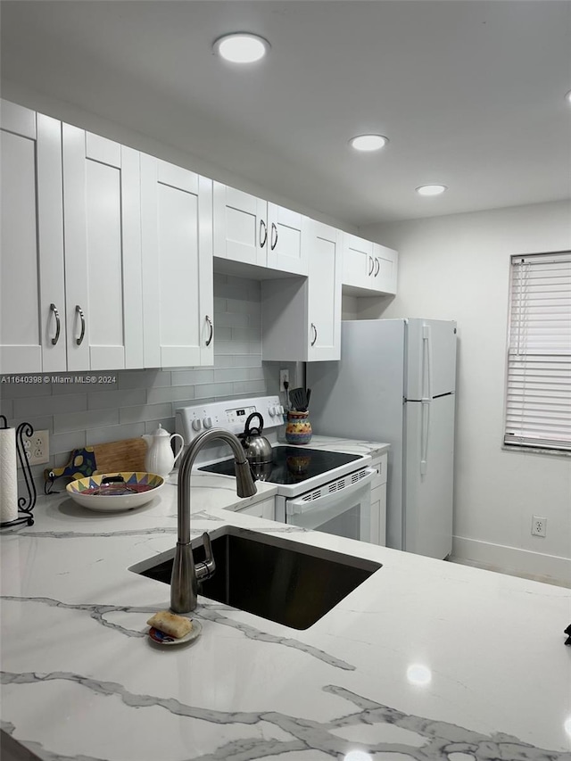 kitchen with tasteful backsplash, sink, white cabinetry, light stone countertops, and white electric range