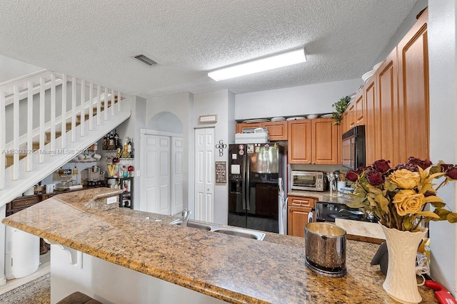 kitchen featuring black appliances, a textured ceiling, kitchen peninsula, and sink