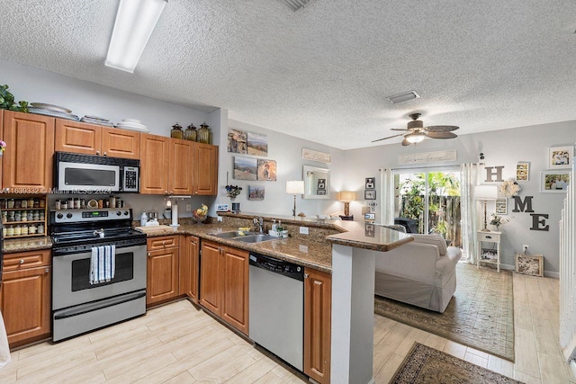 kitchen with light wood-type flooring, appliances with stainless steel finishes, sink, kitchen peninsula, and ceiling fan