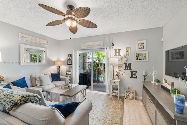 living room with light hardwood / wood-style flooring, ceiling fan, a textured ceiling, and a healthy amount of sunlight