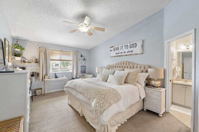 bedroom with light colored carpet, lofted ceiling, ceiling fan, connected bathroom, and a textured ceiling