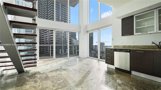 kitchen with a high ceiling, sink, dark brown cabinetry, and stainless steel dishwasher