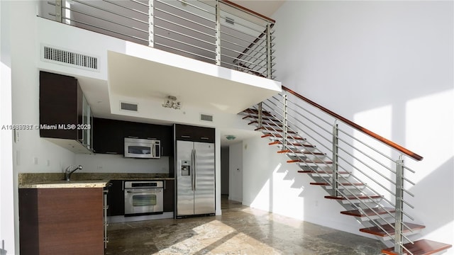 interior space with sink, stainless steel appliances, a high ceiling, and concrete floors