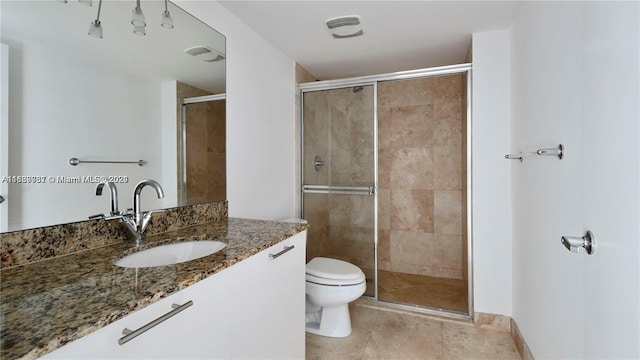 bathroom with tile patterned flooring, an enclosed shower, vanity, and toilet