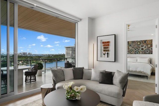 living room featuring floor to ceiling windows, light parquet floors, and a water view