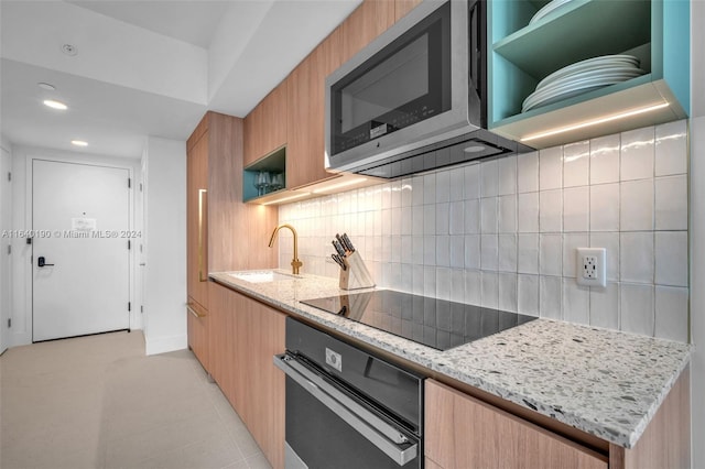 kitchen featuring light tile patterned flooring, stainless steel appliances, light stone countertops, backsplash, and sink