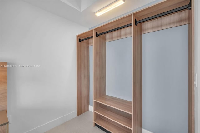 walk in closet with a barn door and light tile patterned floors