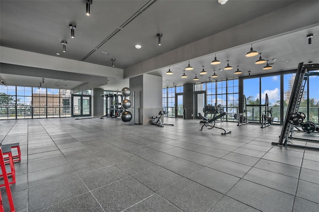 exercise room with a wall of windows, a wealth of natural light, and light tile patterned floors