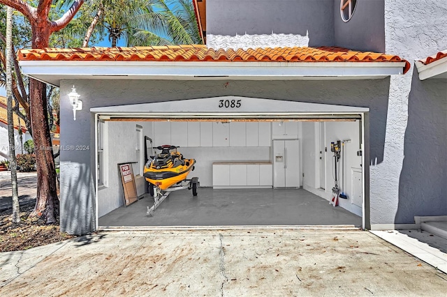 garage featuring white refrigerator with ice dispenser