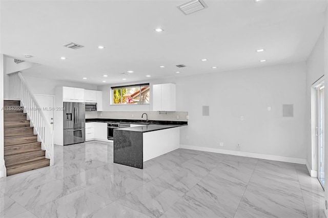 kitchen with stainless steel appliances, white cabinets, kitchen peninsula, and sink