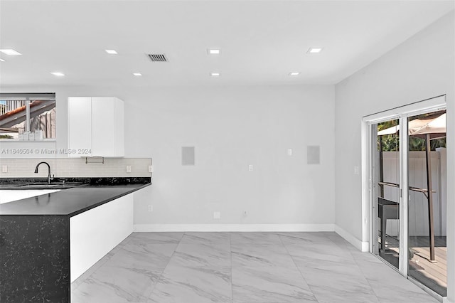 kitchen with white cabinets, sink, and tasteful backsplash