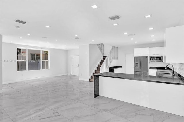 kitchen with decorative backsplash, white cabinetry, sink, and stainless steel appliances