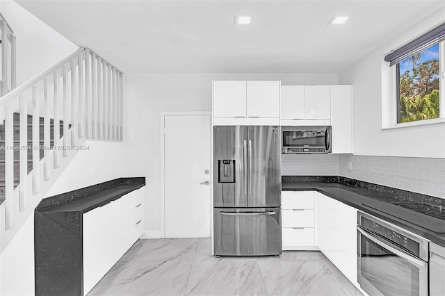 kitchen with tasteful backsplash, dark stone countertops, stainless steel appliances, and white cabinets