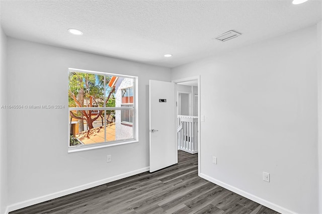 spare room featuring a textured ceiling and dark wood-type flooring