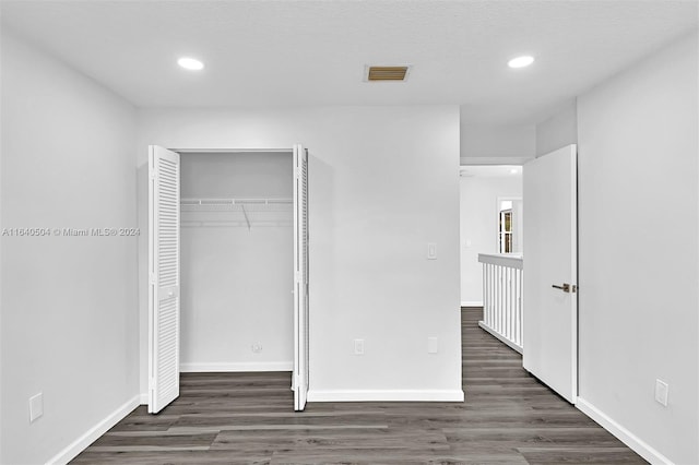 unfurnished bedroom featuring dark hardwood / wood-style flooring and a closet