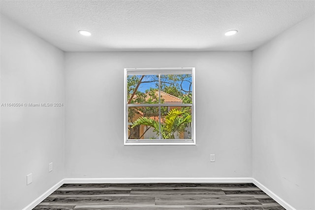 unfurnished room with a textured ceiling and dark wood-type flooring