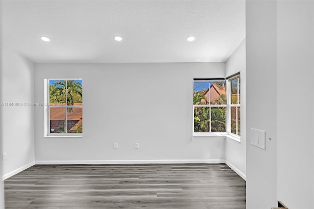 unfurnished room with a textured ceiling and dark hardwood / wood-style floors