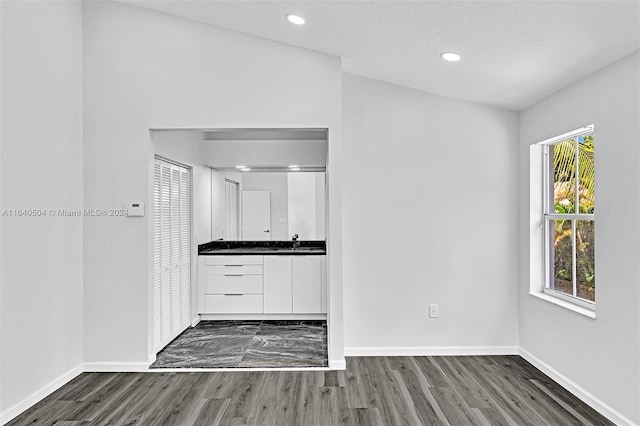 kitchen with white cabinets, a textured ceiling, vaulted ceiling, and dark hardwood / wood-style flooring