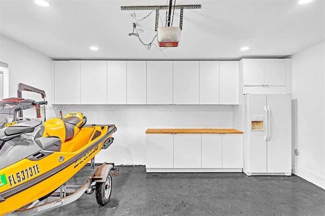 garage with a garage door opener and white refrigerator with ice dispenser