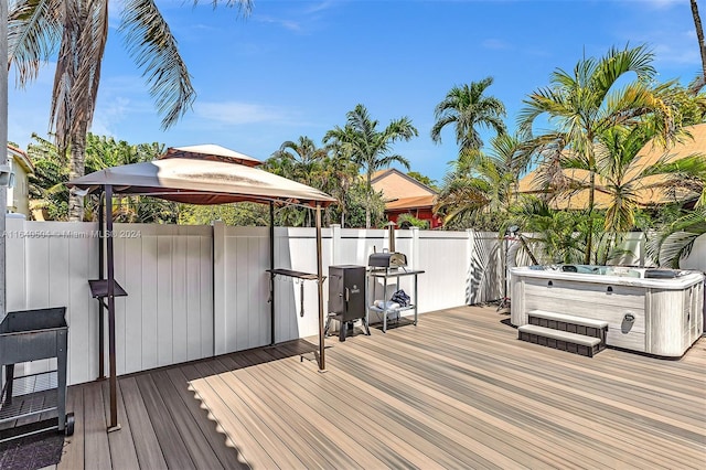 deck featuring a hot tub and a gazebo