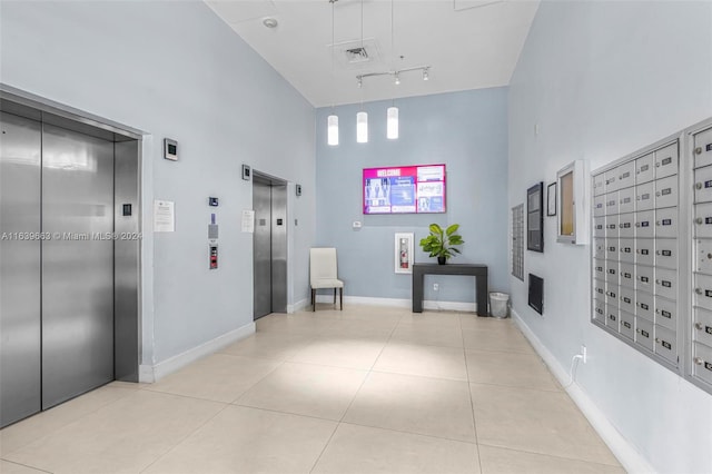 hallway with track lighting, a mail area, elevator, and tile patterned flooring