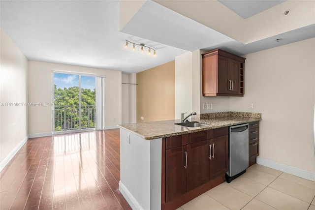 kitchen featuring kitchen peninsula, light stone counters, track lighting, and sink