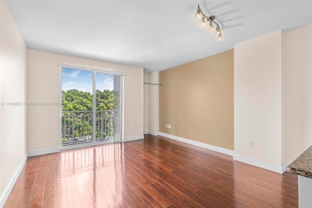 unfurnished room with wood-type flooring, a textured ceiling, and track lighting