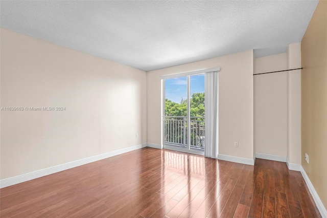 unfurnished bedroom featuring wood-type flooring, a textured ceiling, and access to outside