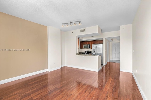 unfurnished living room with dark wood-type flooring, a textured ceiling, and rail lighting