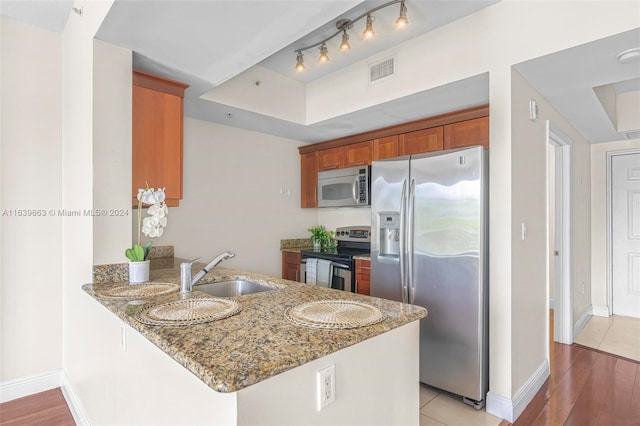 kitchen featuring light hardwood / wood-style flooring, appliances with stainless steel finishes, kitchen peninsula, light stone countertops, and sink