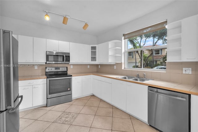 kitchen featuring white cabinetry, backsplash, rail lighting, and stainless steel appliances