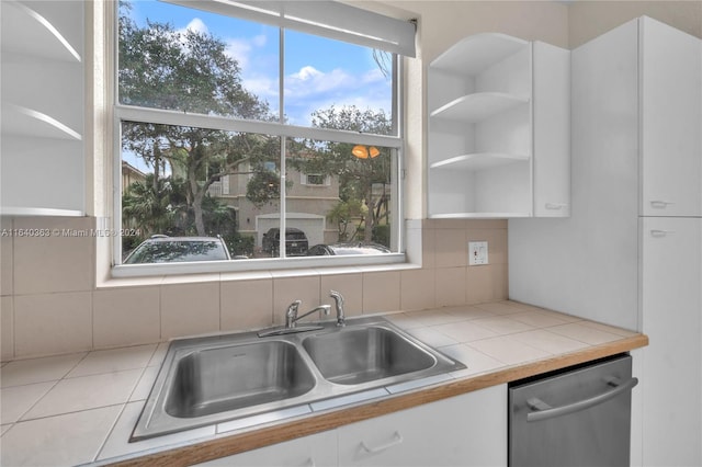 kitchen featuring tasteful backsplash, sink, dishwashing machine, white cabinets, and tile counters